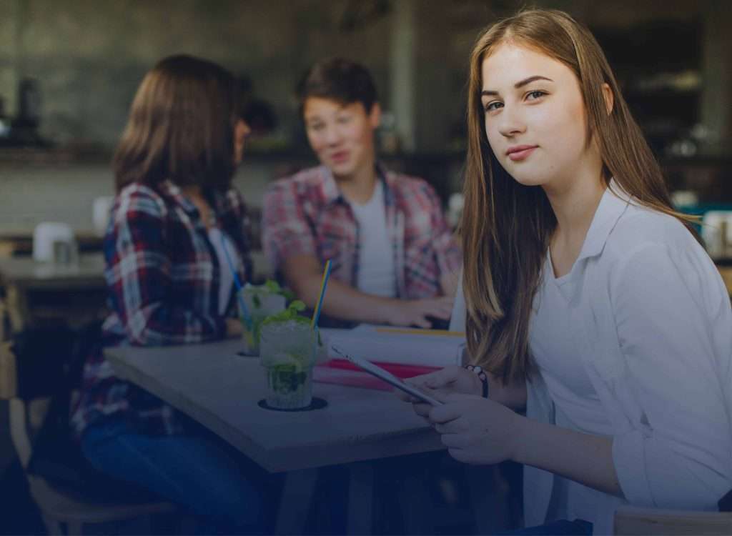 Young woman listens attentively while others speak, demonstrating use of tone, emphasis, and persuasive language techniques.