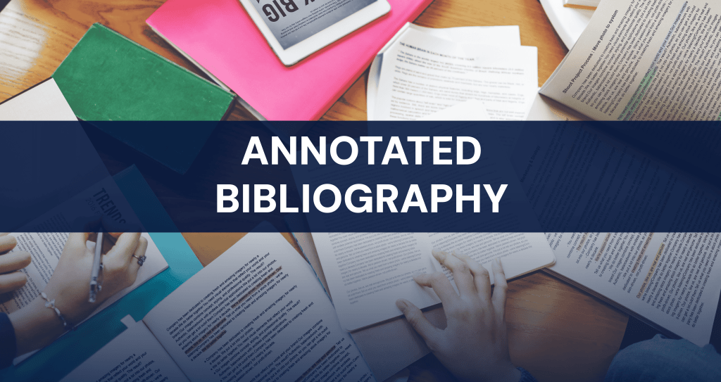 Books and papers on a desk with students writing, illustrating the concept of creating an annotated bibliography for academic research.